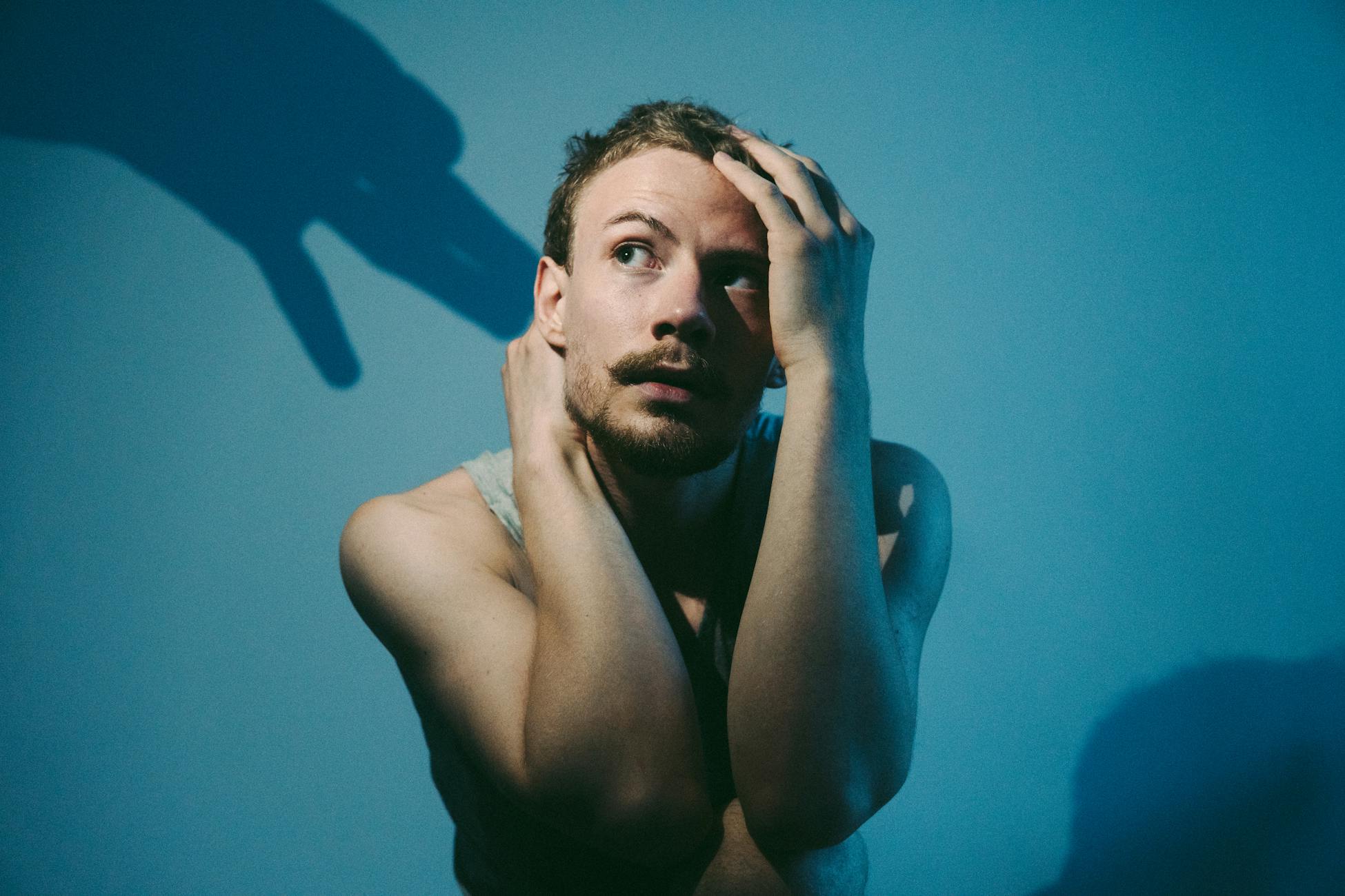 Artistic portrait of a man in blue lighting, contemplating with shadow play.