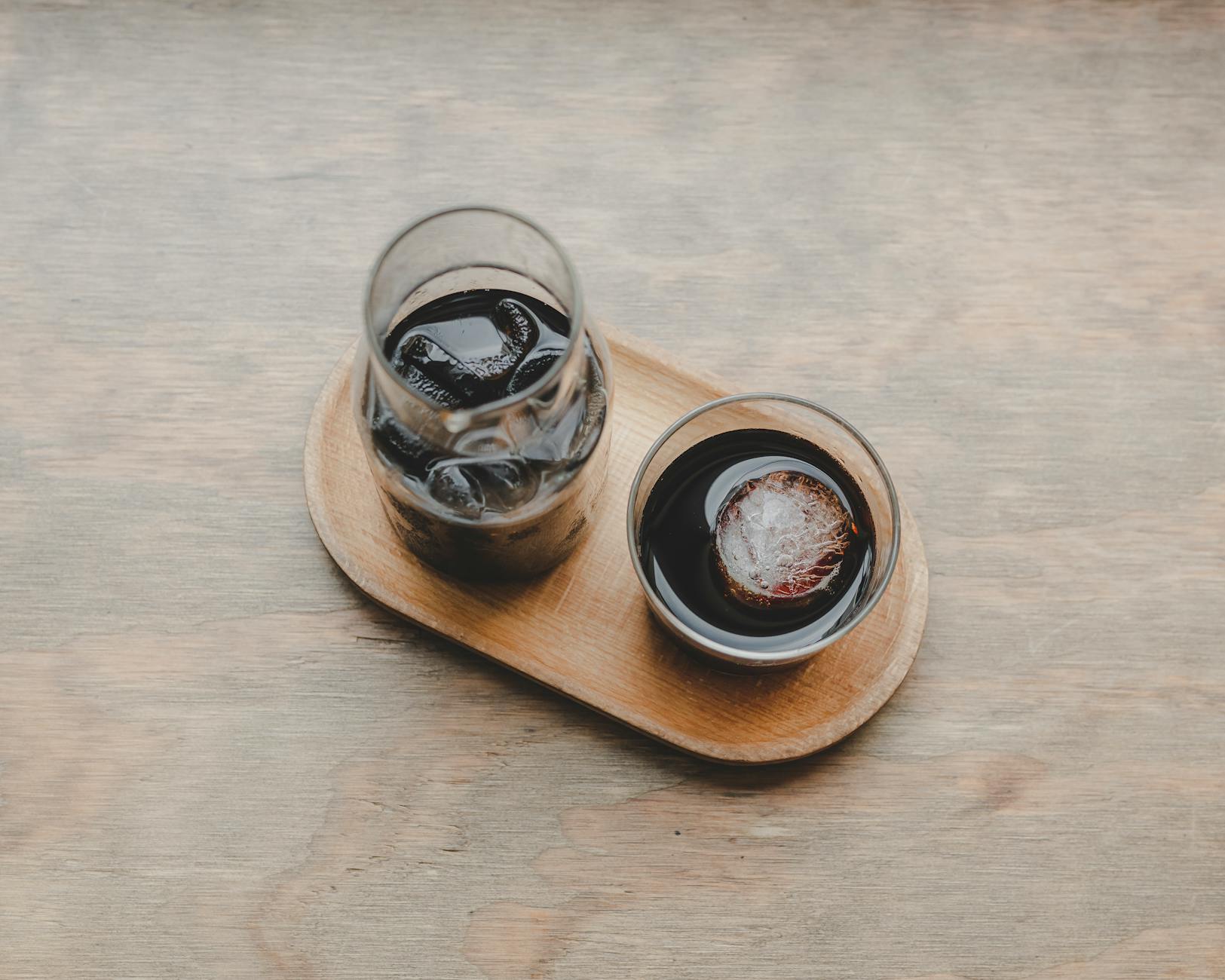 Aesthetic shot of iced coffee beverages on a wooden tray, showcasing a simple and relaxing setup.