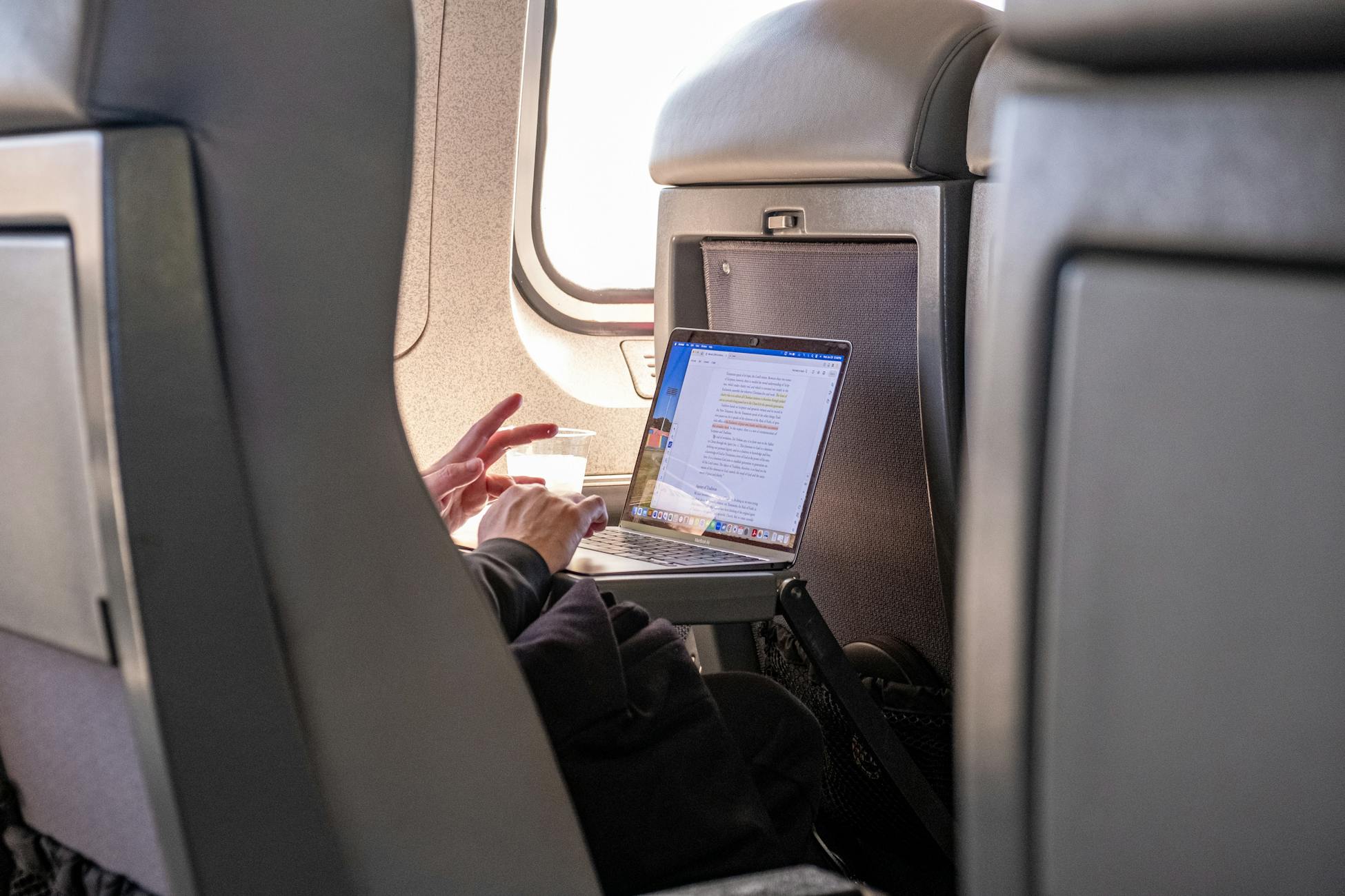 Passenger working on a laptop during flight, highlighting travel productivity.