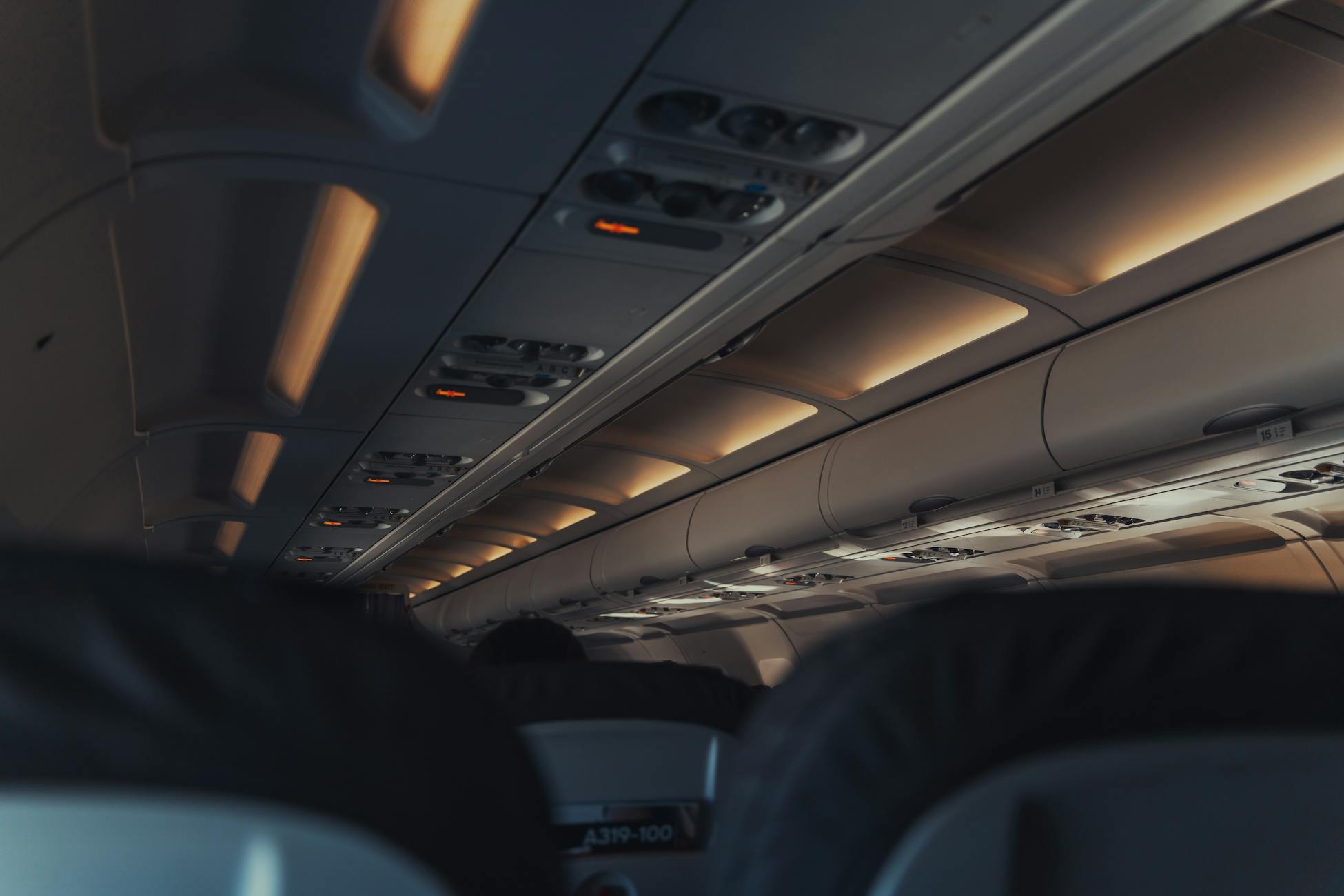 Interior view of a commercial airplane cabin focusing on overhead lights and seats.