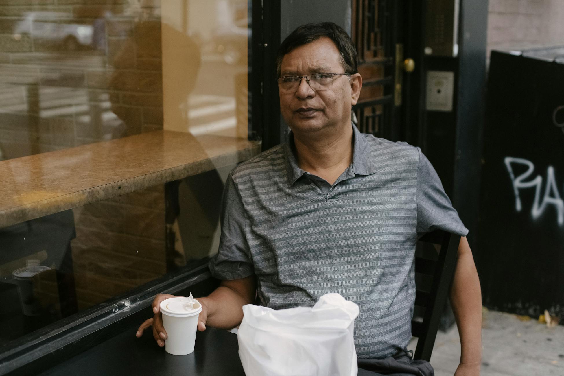 A contemplative middle-aged man enjoying a coffee break at a cozy café window.