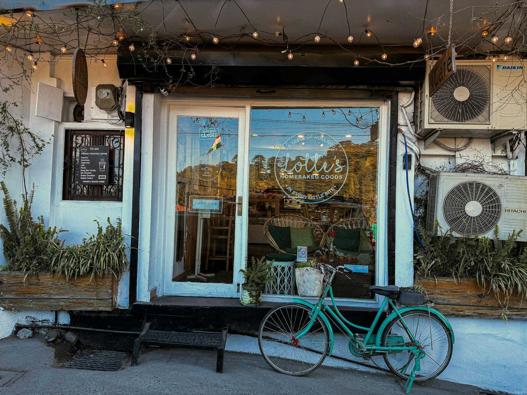 Cozy exterior of a cafe adorned with plants and a vintage bicycle parked outside.