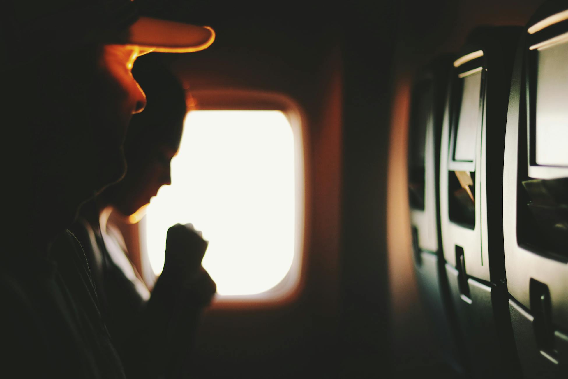 Silhouetted passengers sitting by a window during a flight, capturing a serene travel moment.