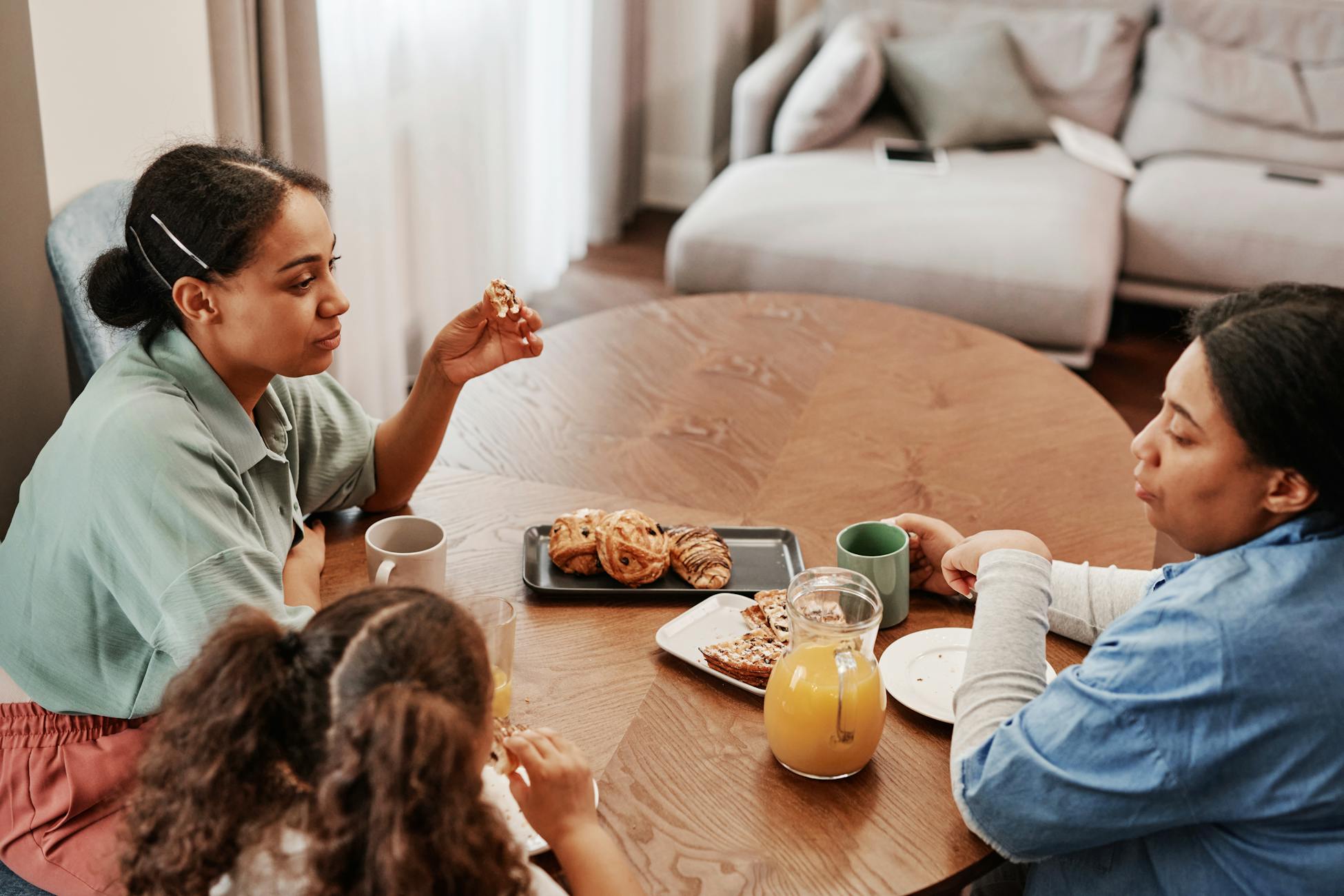 A cozy morning family breakfast scene with pastries and orange juice at a wooden table.