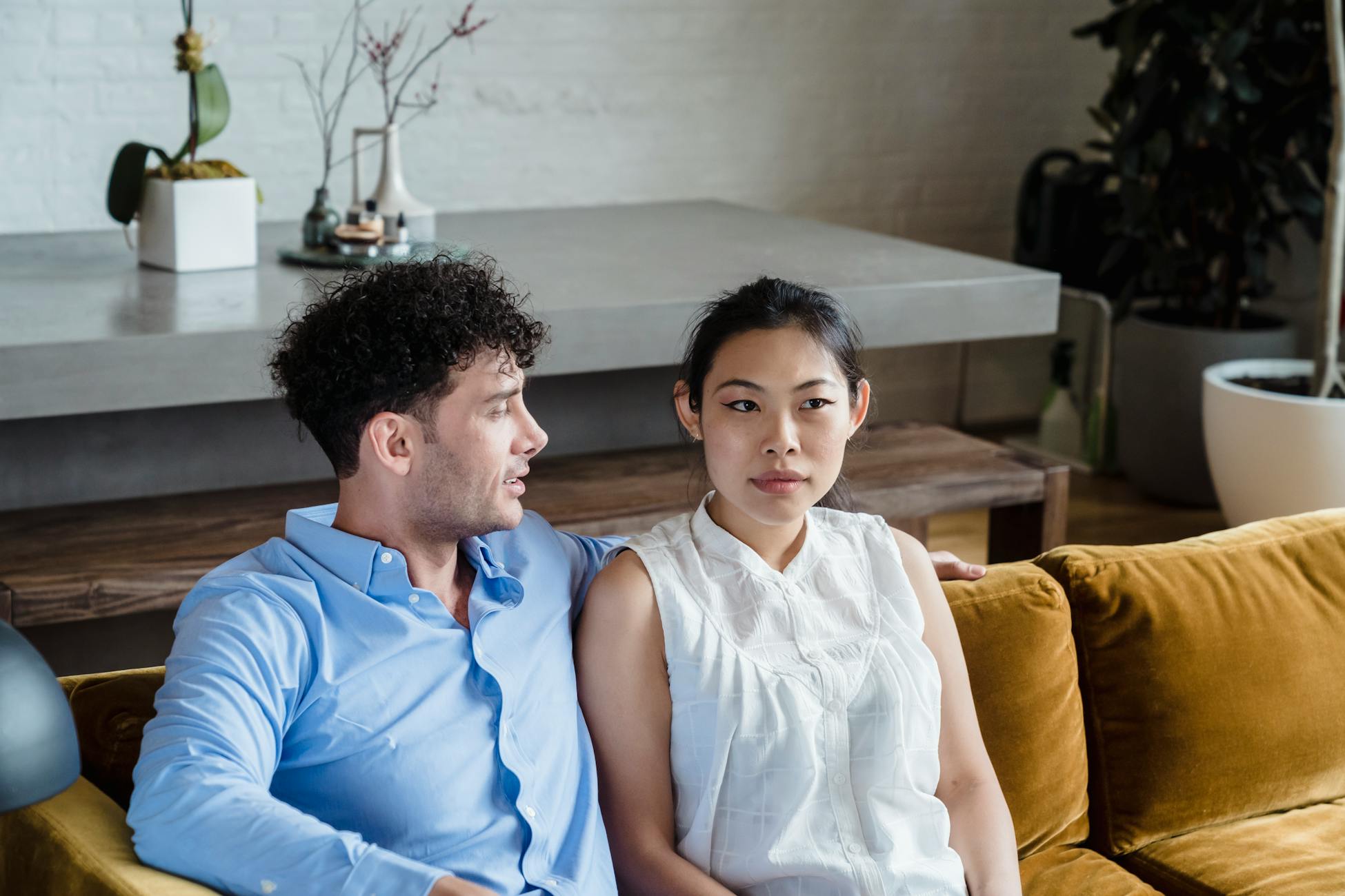 A young interracial couple sitting together on a cozy sofa in a modern living room.