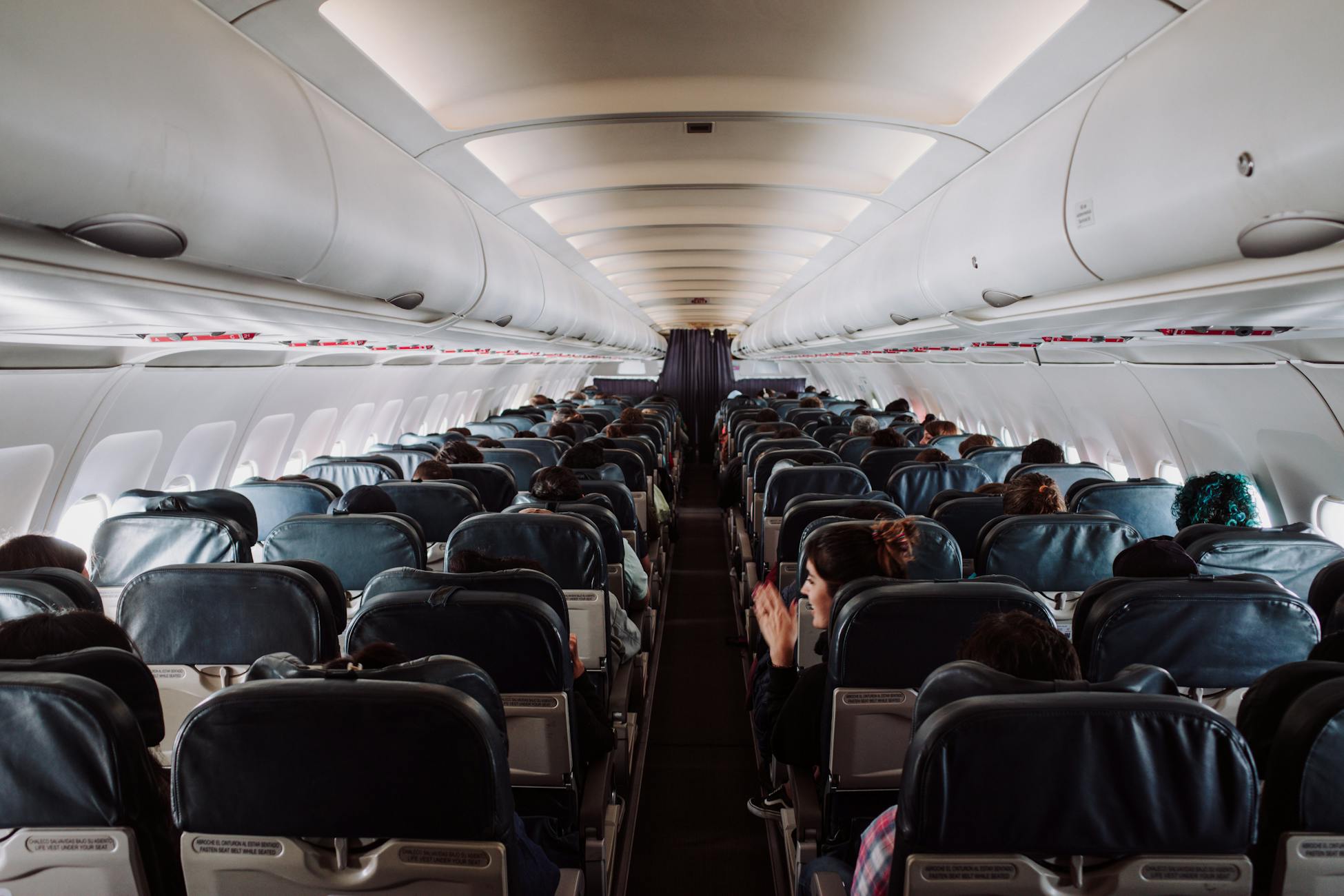 A view of passengers seated inside a commercial airplane cabin during flight.