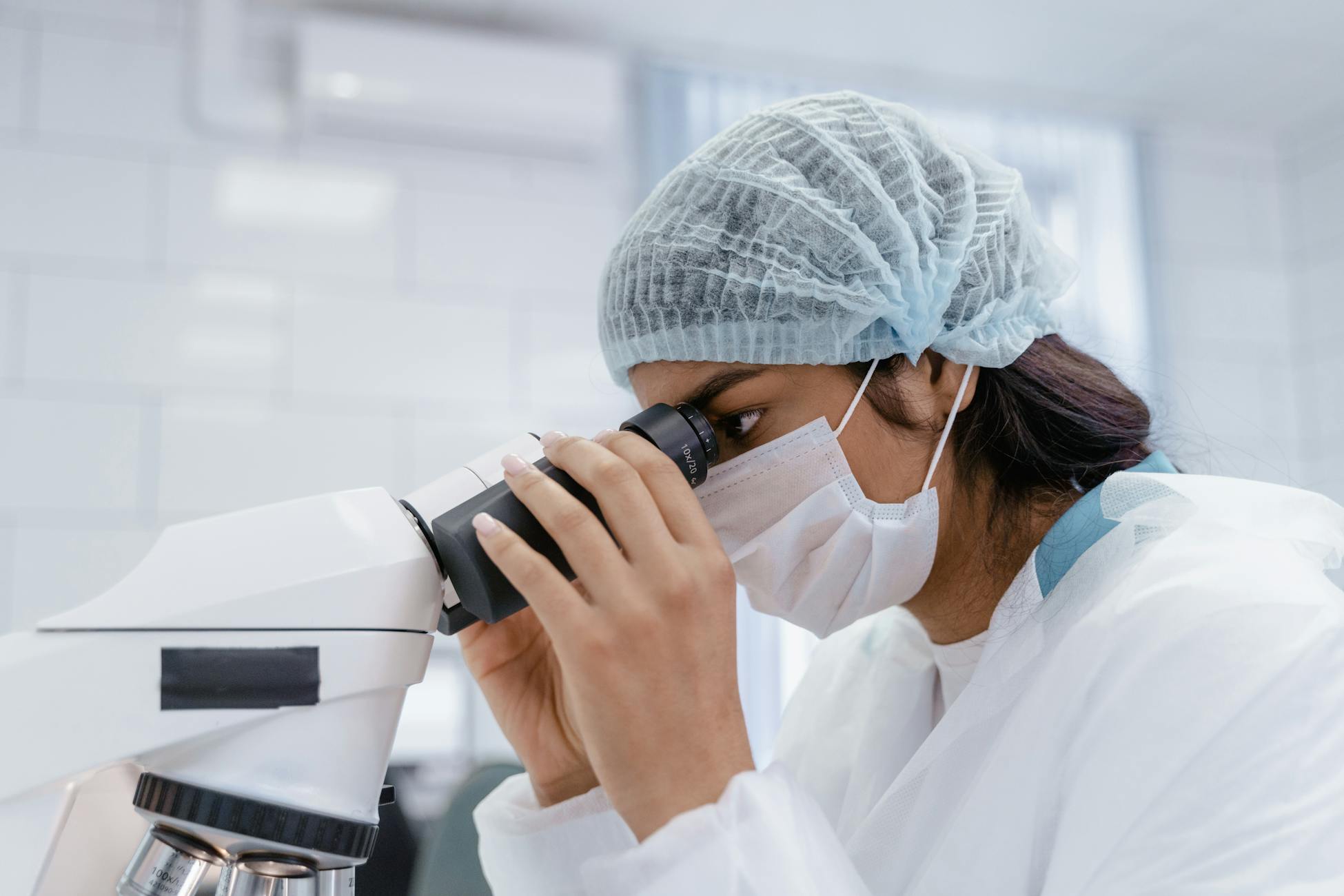 A female scientist uses a microscope in a laboratory, focusing on research and analysis.