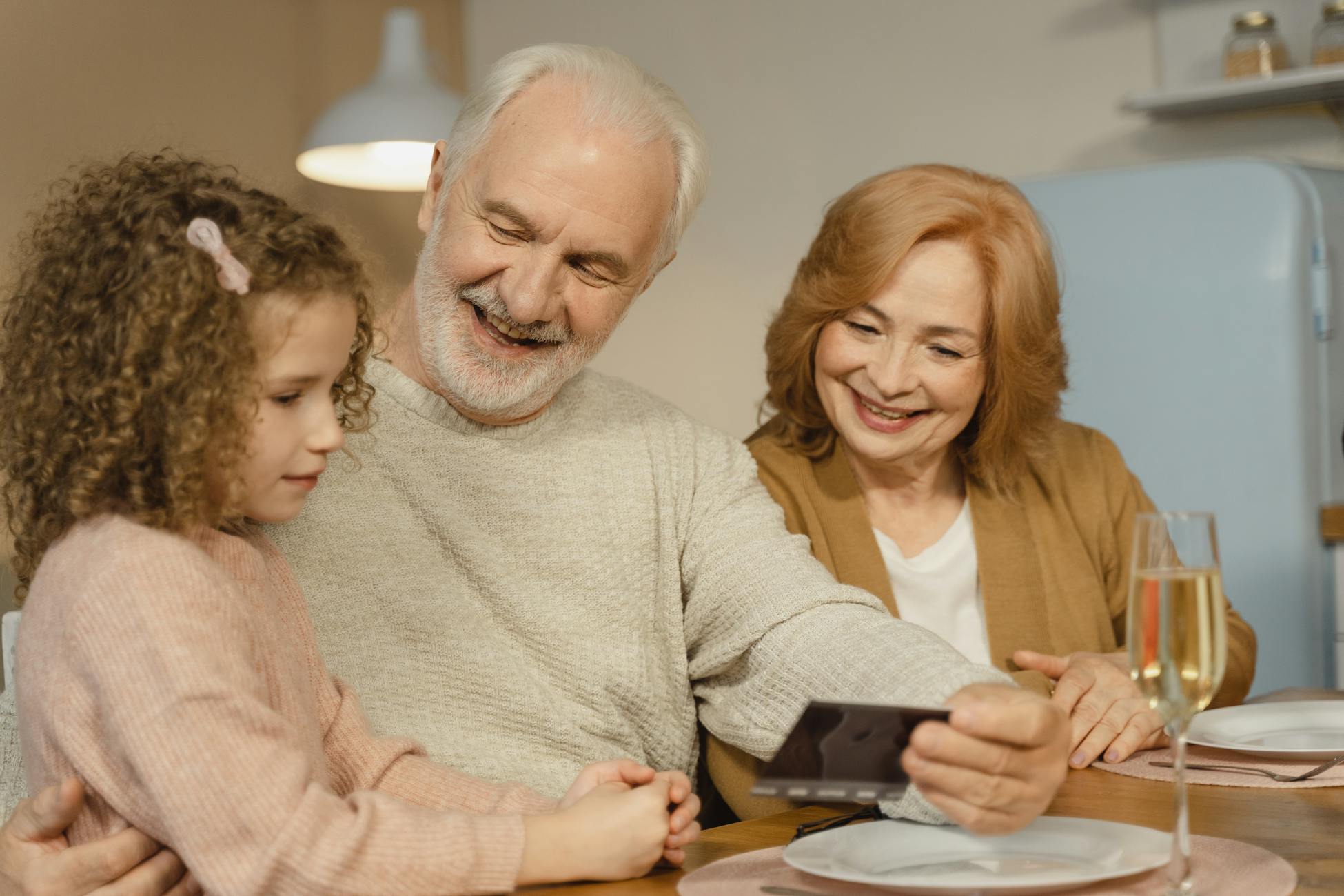 Smiling grandparents enjoying time with their granddaughter indoors at home.