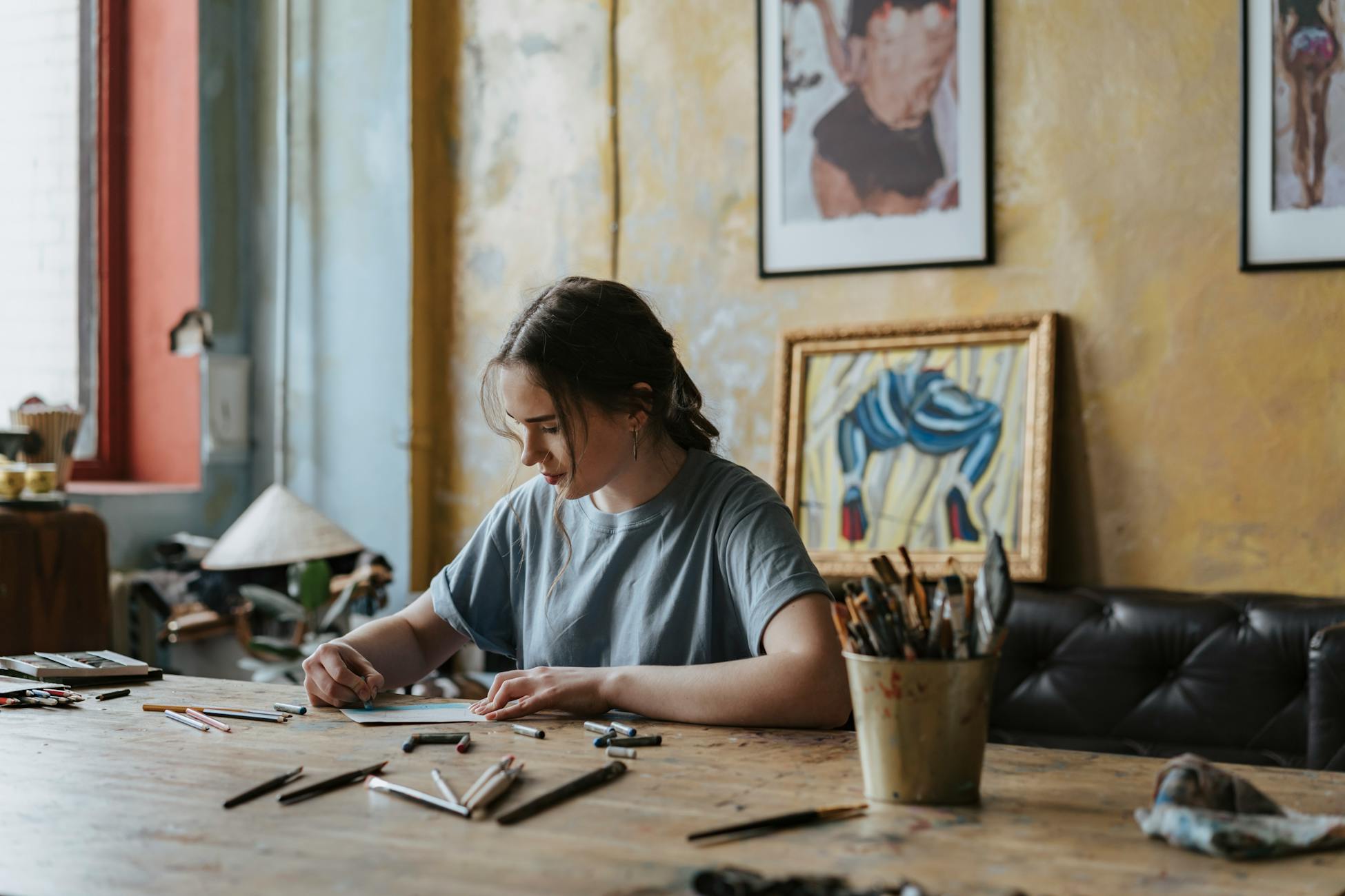 A young woman engaging in drawing activities at her home studio, surrounded by artistic tools.